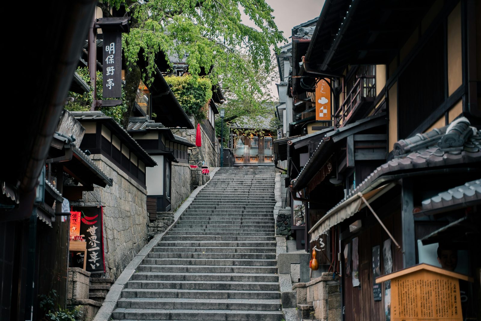 A quiet stone-stepped street in Kyoto, lined with traditional wooden houses